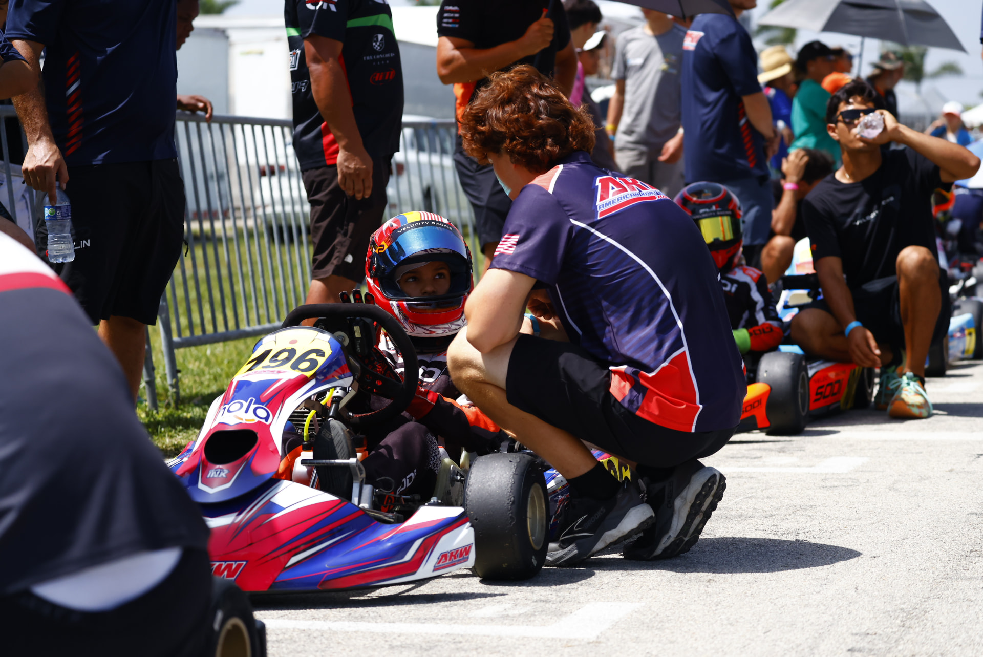 AKW Racing coach working with a young driver on the grid